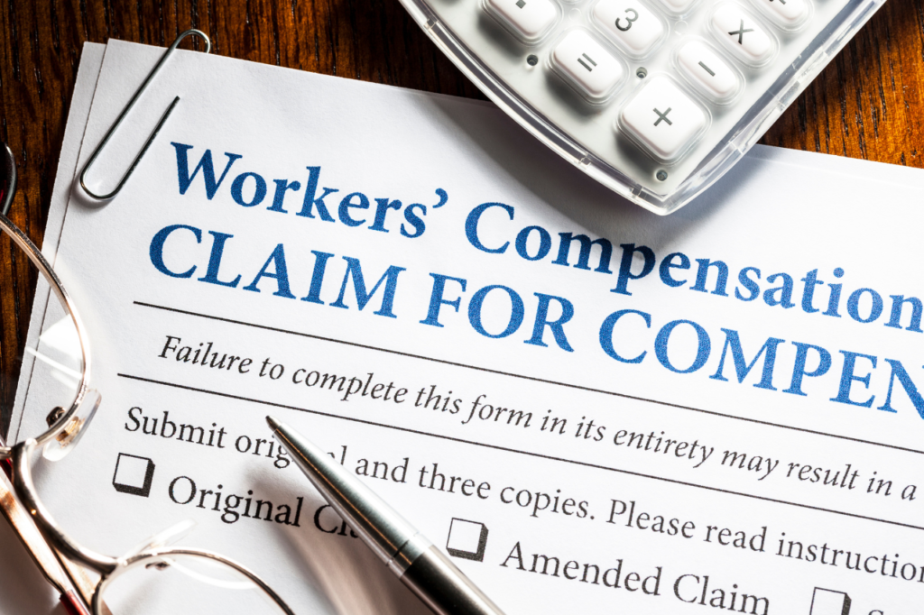 Workers' compensation claim form with glasses and calculator, representing the claims process and policy evaluation.